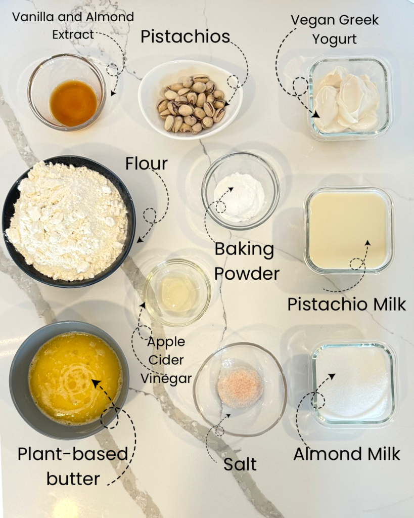 A collection of ingredients for pistachio cake, arranged in separate dishes, including flour, sugar, and pistachios.