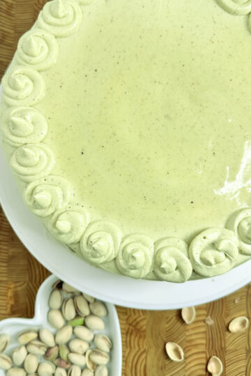 A vegan pistachio cake elegantly presented on a heart-shaped plate, showcasing its delightful green hue and texture