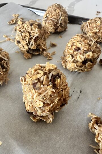 A baking sheet filled with freshly made homemade granola balls, showcasing their round shape and golden-brown color.