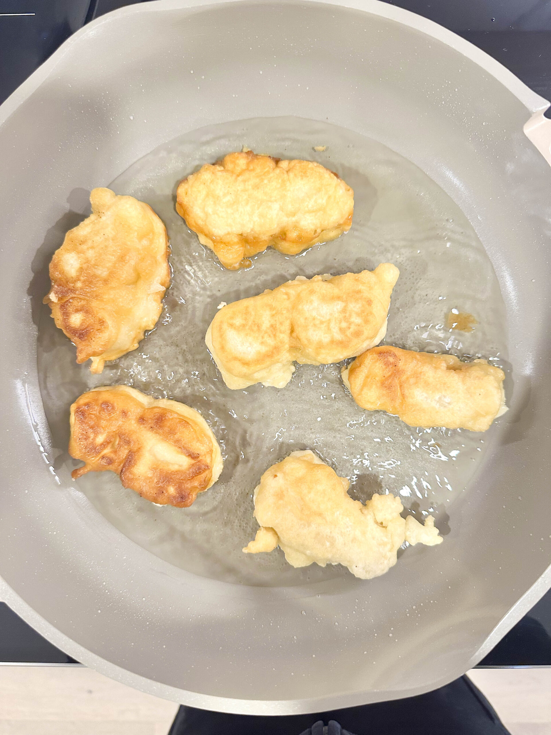 Crispy beer-battered tofu fillets frying in a pan, golden brown and bubbling in hot oil.