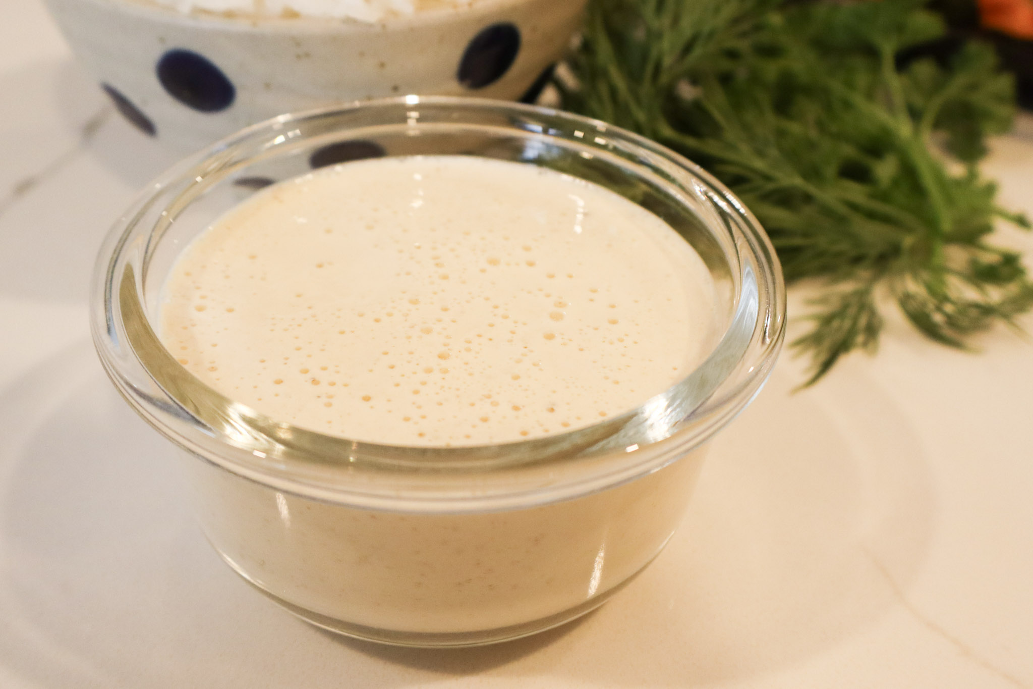 A clear bowl with a creamy tahini dressing displayed