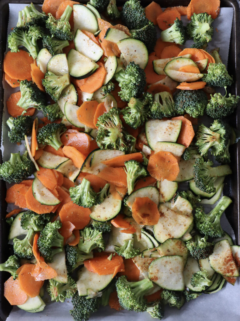 A tray filled with fresh uncooked vegetables, prominently featuring vibrant orange carrots and green broccoli florets.
